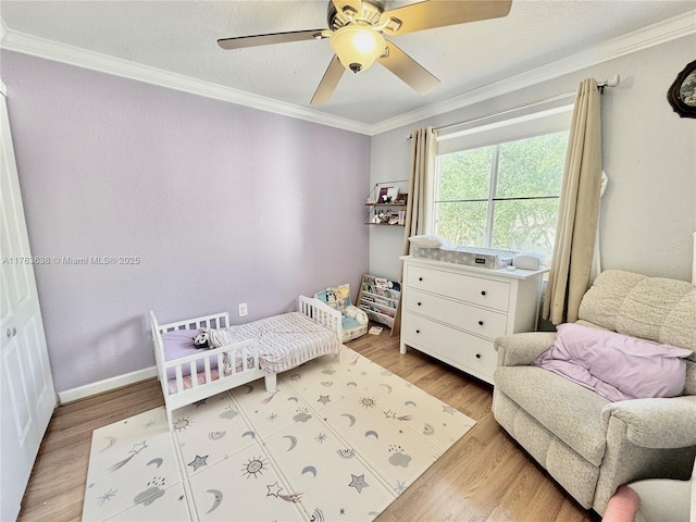 bedroom with baseboards, a ceiling fan, light wood-style floors, and ornamental molding