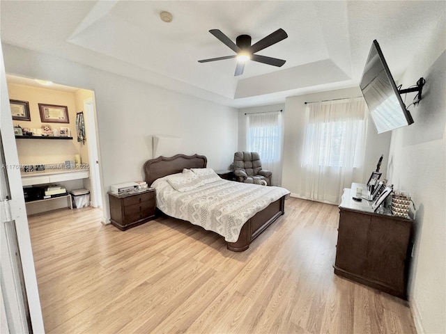 bedroom featuring a tray ceiling, light wood-type flooring, and ceiling fan