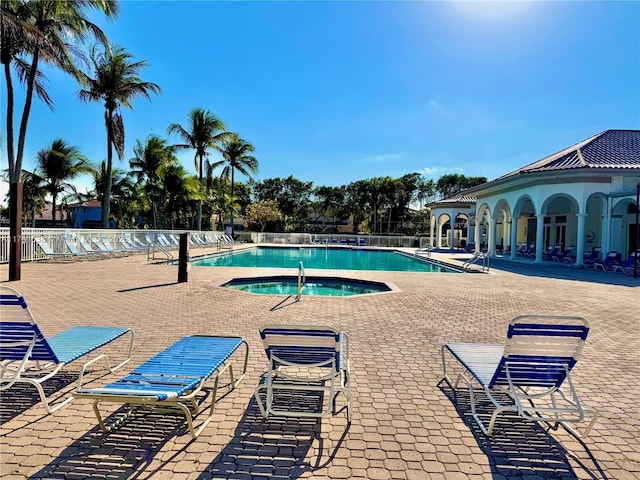 community pool featuring a patio area, a community hot tub, and fence