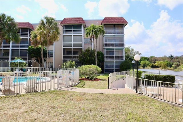 view of building exterior with a community pool and fence