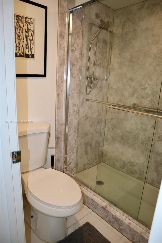 full bath with a shower stall, toilet, and tile patterned floors