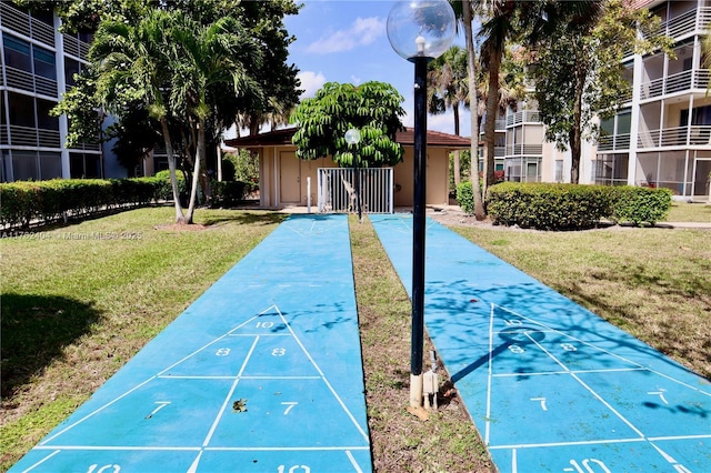 view of property's community with a lawn and shuffleboard