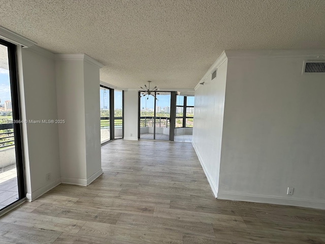 hallway with visible vents, light wood finished floors, floor to ceiling windows, a textured ceiling, and a chandelier