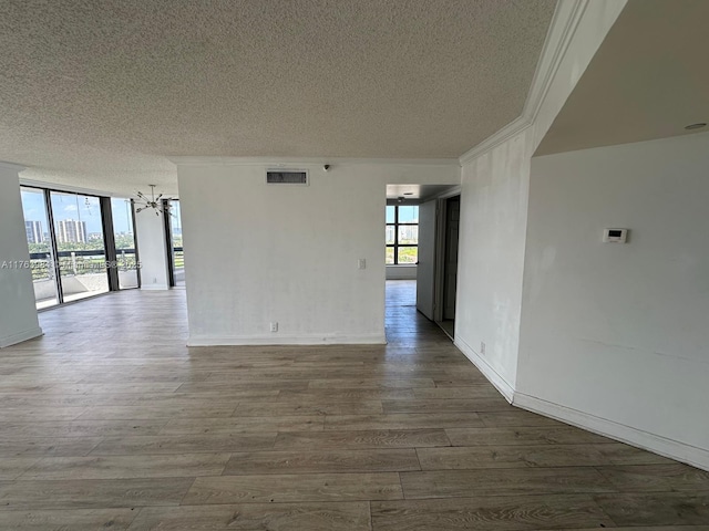 spare room featuring visible vents, plenty of natural light, an inviting chandelier, and floor to ceiling windows