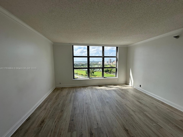 empty room with a textured ceiling, dark wood-style flooring, and ornamental molding