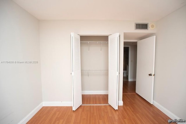 unfurnished bedroom featuring a closet, baseboards, visible vents, and light wood-style flooring