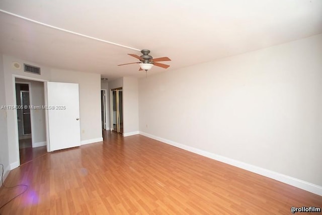 empty room featuring wood finished floors, a ceiling fan, visible vents, and baseboards