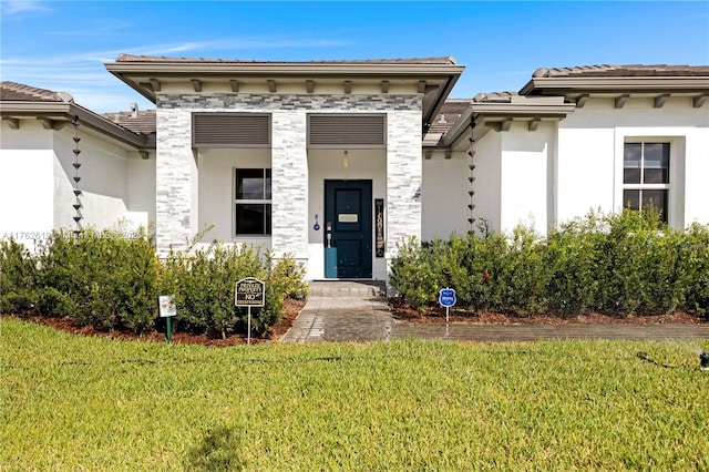 view of front facade with a front lawn, a tiled roof, and stucco siding