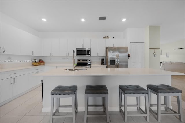 kitchen with visible vents, a sink, stainless steel appliances, light countertops, and a kitchen breakfast bar