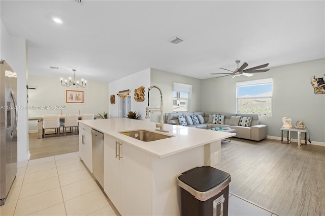 kitchen featuring visible vents, a center island with sink, a sink, stainless steel appliances, and light countertops