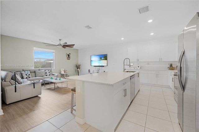 kitchen with visible vents, ceiling fan, open floor plan, appliances with stainless steel finishes, and a sink