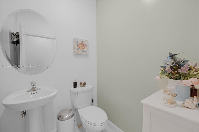 half bath featuring baseboards and toilet