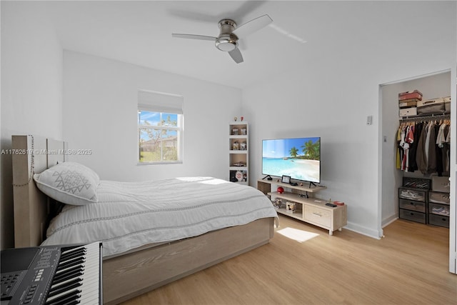 bedroom with a spacious closet, baseboards, ceiling fan, light wood-style flooring, and a closet