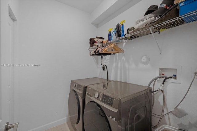 laundry room with laundry area, washing machine and dryer, baseboards, and tile patterned floors