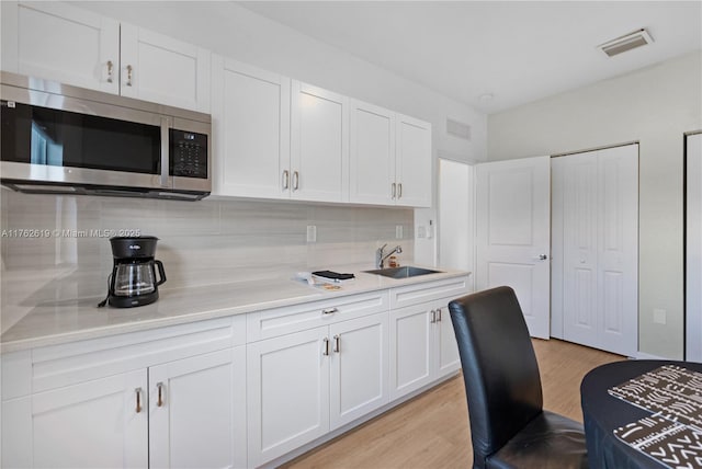 29081 SW 168th Ct, Homestead, FL 33030 - kitchen with stainless steel microwave, a sink, tasteful backsplash, white cabinetry, and light countertops