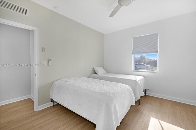 bedroom with ceiling fan, visible vents, baseboards, and wood finished floors