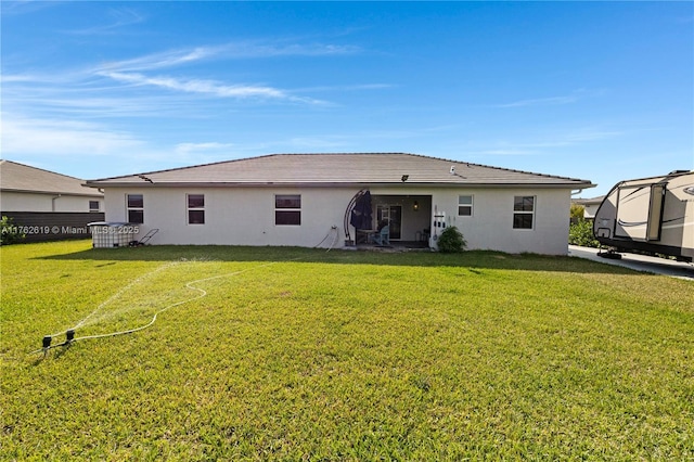 back of property with stucco siding and a yard