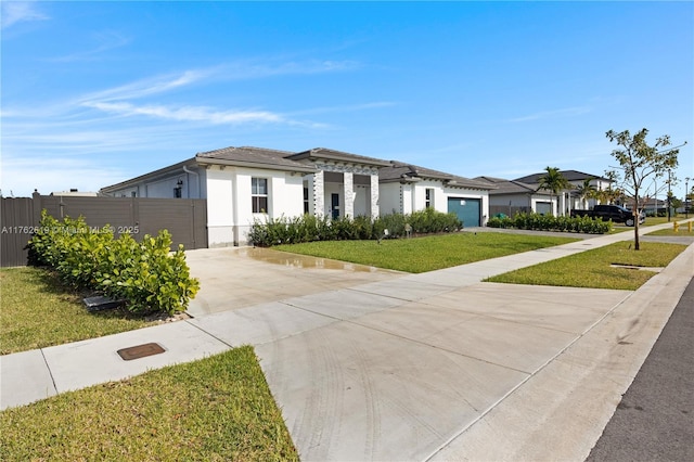 prairie-style home with fence, a front yard, stucco siding, a garage, and driveway