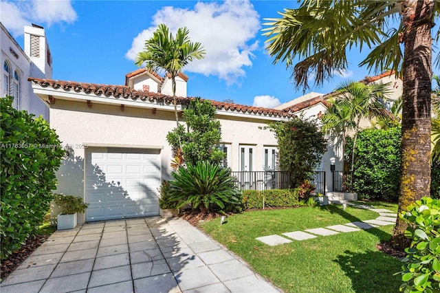 mediterranean / spanish house featuring a tile roof, a front lawn, driveway, and stucco siding