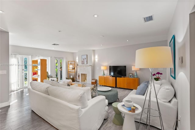 living area featuring wood finished floors, visible vents, baseboards, a fireplace, and recessed lighting