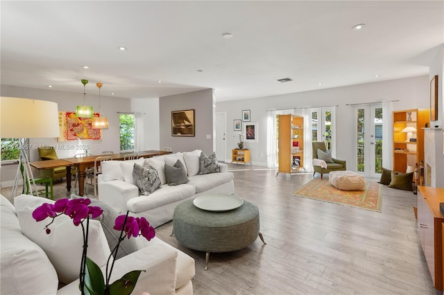 living room with visible vents, baseboards, light wood-style flooring, recessed lighting, and french doors