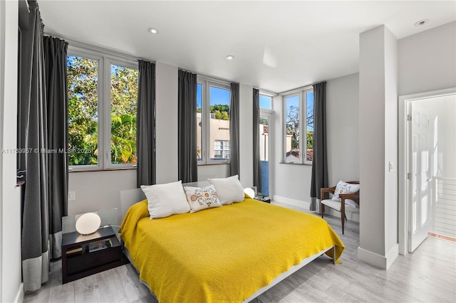 bedroom featuring recessed lighting, multiple windows, baseboards, and light wood-style floors