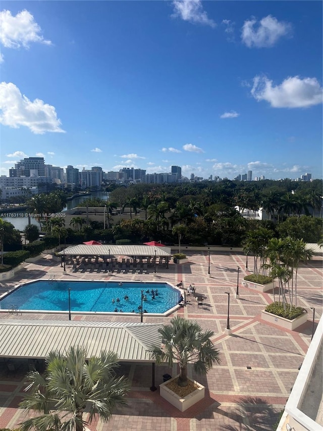 community pool with a patio, a view of city, and a water view