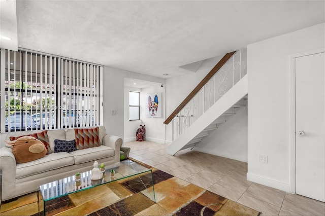 tiled living area featuring stairs and baseboards