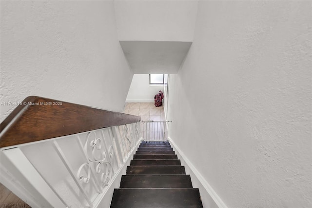 stairway with a textured wall and baseboards