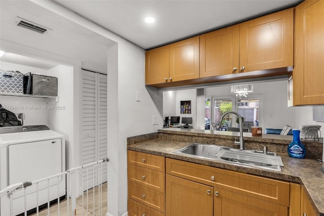 kitchen with visible vents, washer / clothes dryer, light tile patterned flooring, a sink, and dark countertops