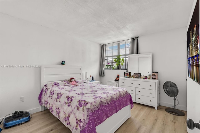 bedroom with a textured ceiling, light wood-type flooring, and baseboards