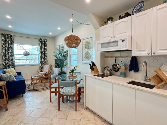 kitchen featuring white microwave, tasteful backsplash, light countertops, and a sink