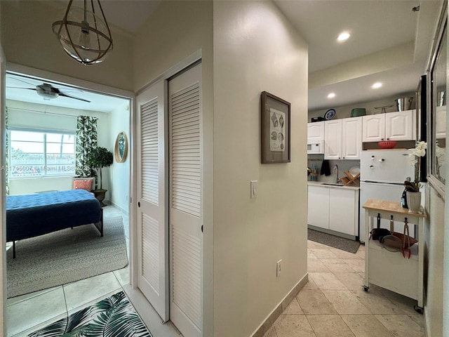 hallway featuring a sink, baseboards, recessed lighting, and light tile patterned floors