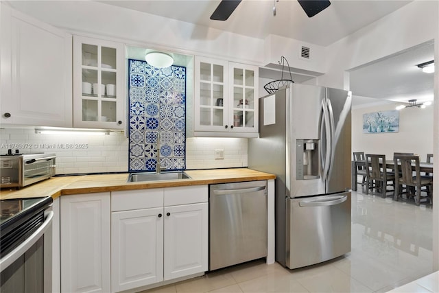 kitchen featuring a sink, stainless steel appliances, wooden counters, and visible vents