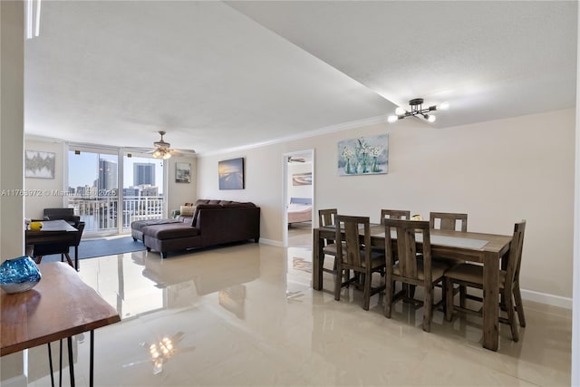 dining space with crown molding, a view of city, ceiling fan with notable chandelier, and baseboards