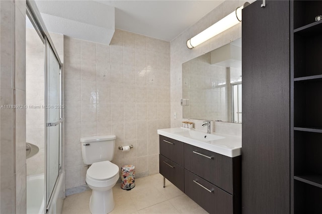 full bathroom featuring toilet, tile walls, vanity, and tile patterned flooring