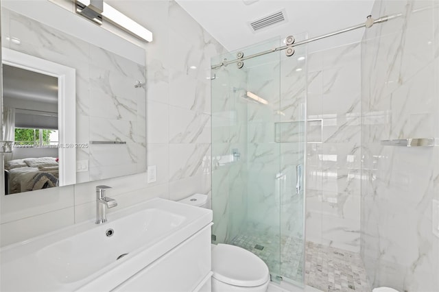 ensuite bathroom featuring visible vents, a marble finish shower, tile walls, toilet, and connected bathroom