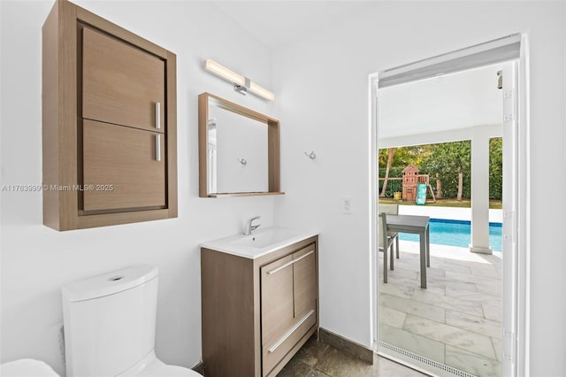 half bath featuring toilet, vanity, and baseboards