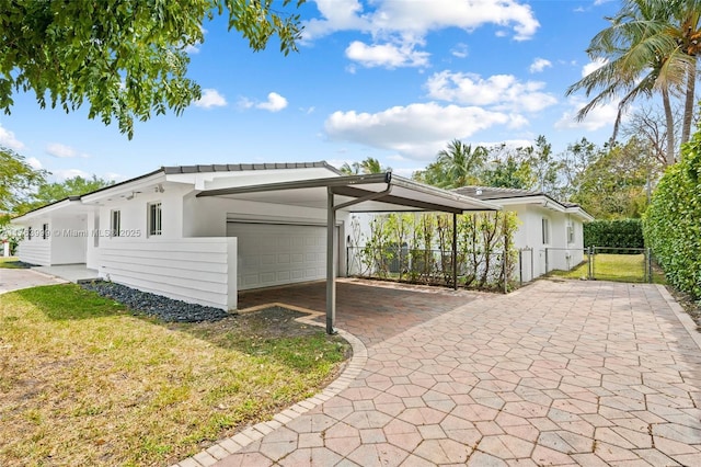 view of home's exterior with fence, a yard, a garage, a carport, and driveway