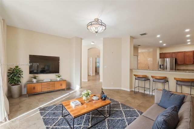 living room featuring arched walkways, light tile patterned floors, recessed lighting, and baseboards