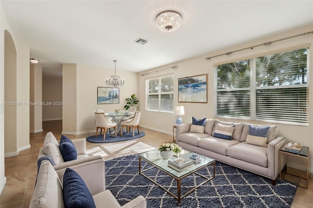 living area featuring visible vents, arched walkways, baseboards, and a chandelier