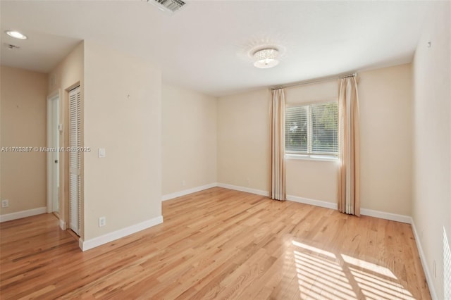 spare room with visible vents, baseboards, and wood finished floors