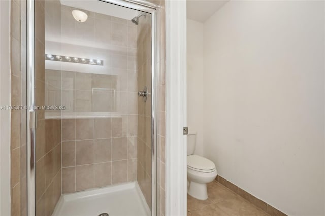 bathroom with tile patterned floors, a shower stall, toilet, and baseboards