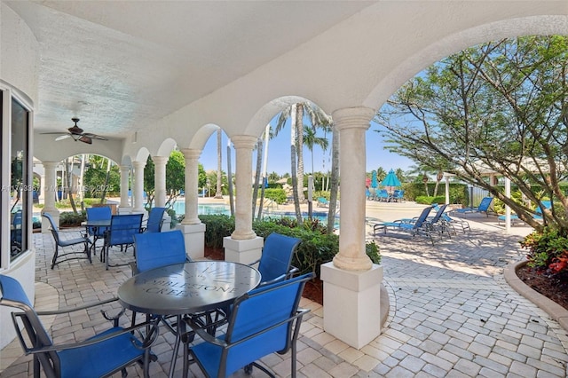 view of patio featuring ceiling fan, a community pool, and outdoor dining space