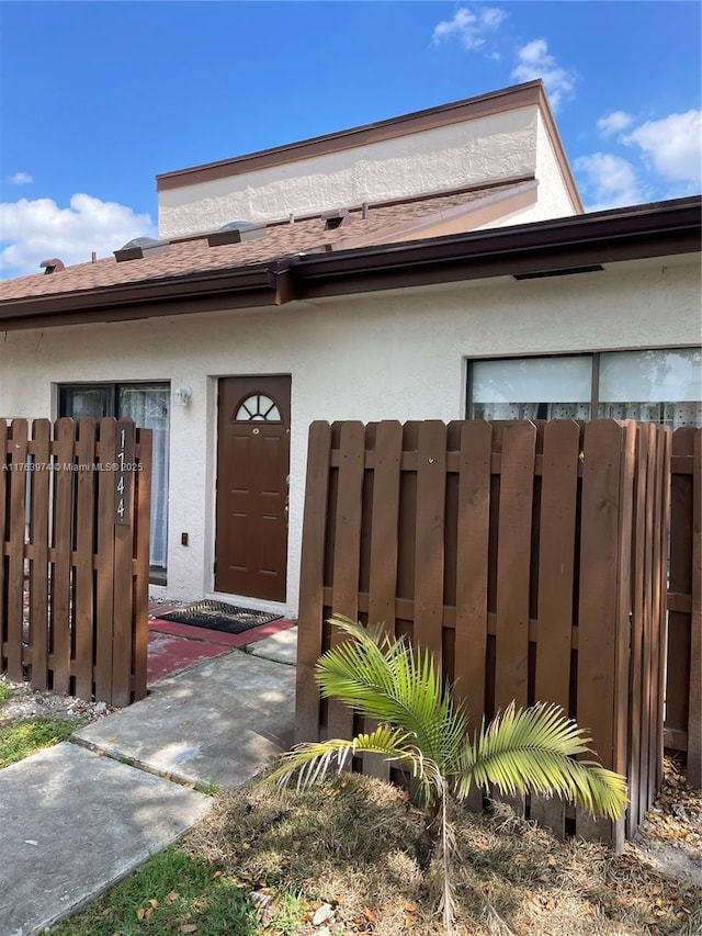 entrance to property featuring fence and stucco siding