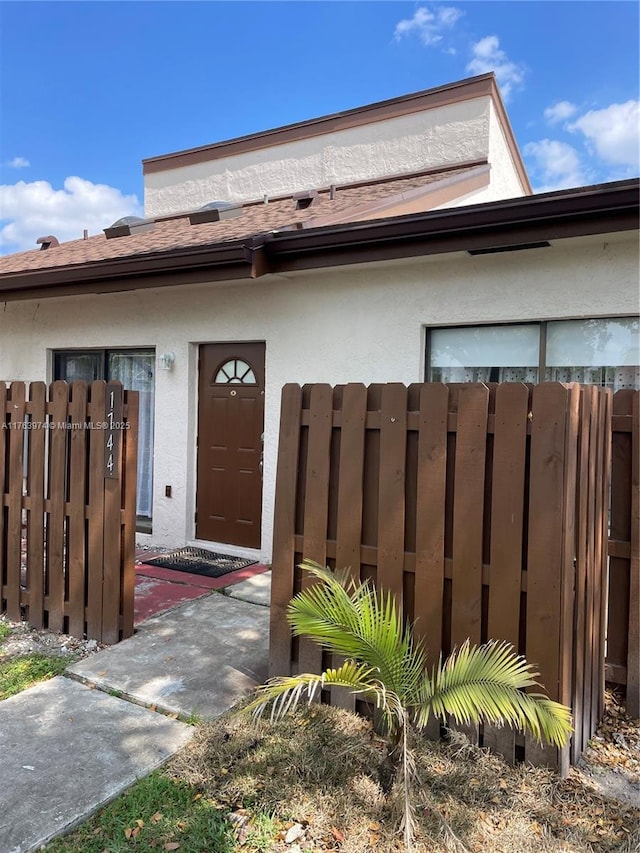 entrance to property featuring fence and stucco siding