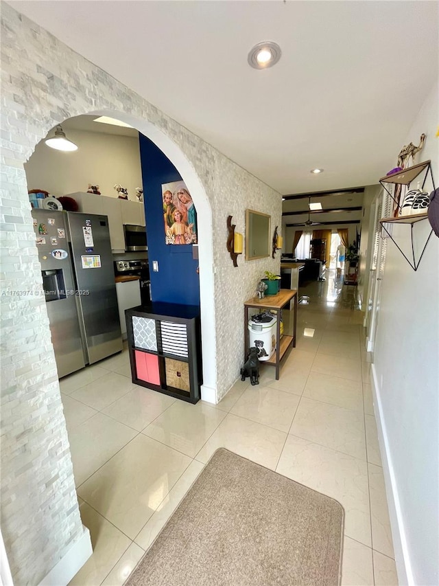 hall featuring arched walkways, light tile patterned floors, recessed lighting, and baseboards