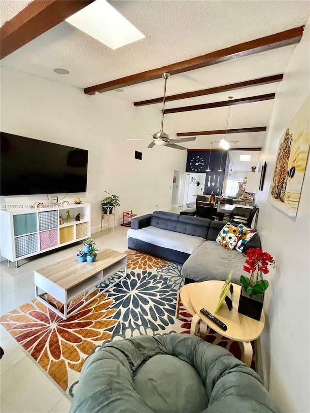 living area featuring beam ceiling, tile patterned floors, a textured ceiling, and ceiling fan