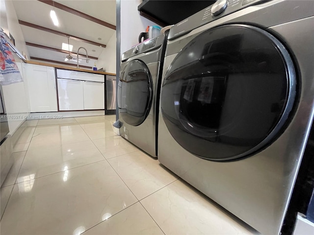 clothes washing area featuring a sink, washing machine and dryer, light tile patterned flooring, and laundry area