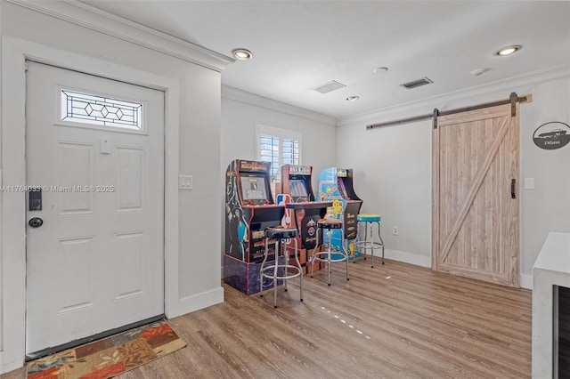 entrance foyer featuring visible vents, wood finished floors, a barn door, crown molding, and baseboards